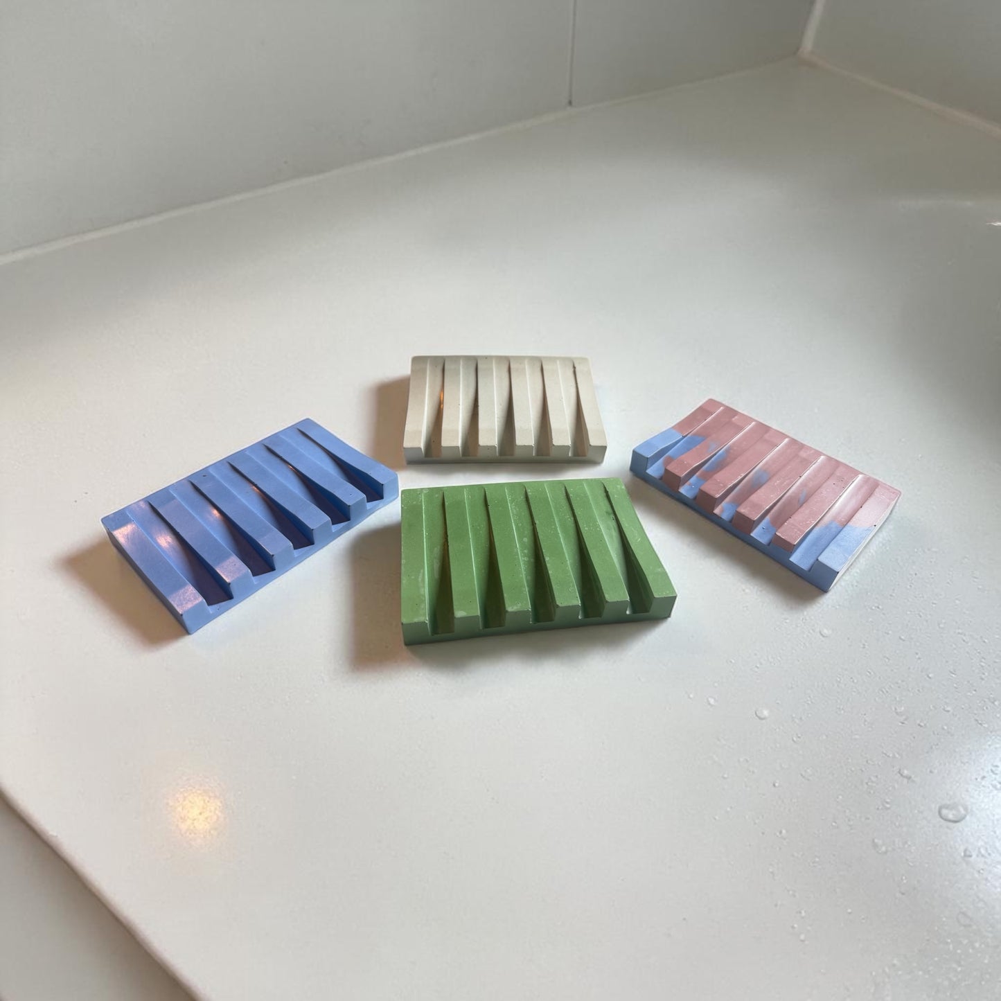 Four rectangular soap dishes with striped patterns on a white surface