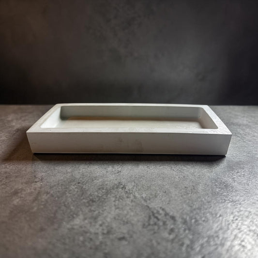 Rectangular white concrete tray on a textured gray surface with a dark background