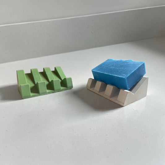 Two soap dishes, one with a soap on it.