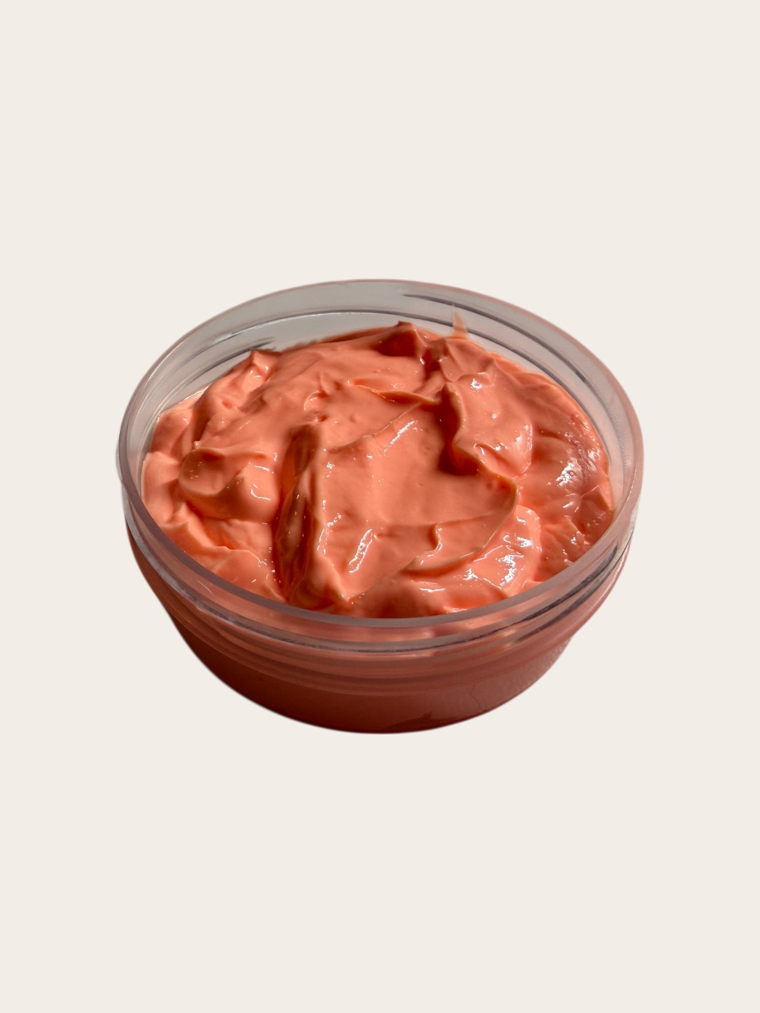 Jar of pinkish body butter on a light beige background